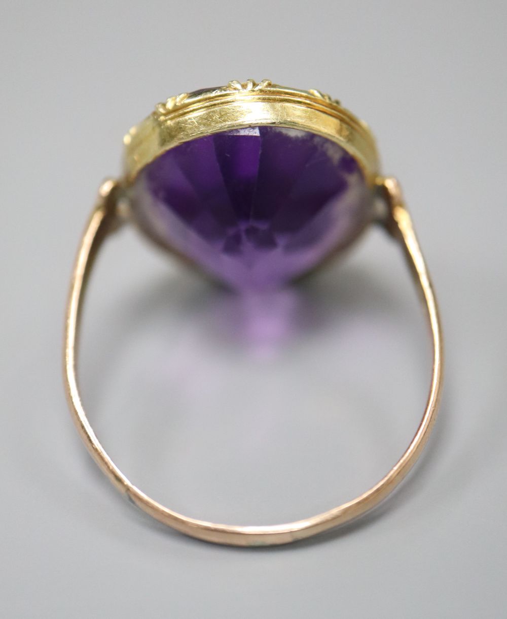 A 19th century gold and amethyst dress ring (tests as 9ct), with collet setting and carved scrolled shoulders